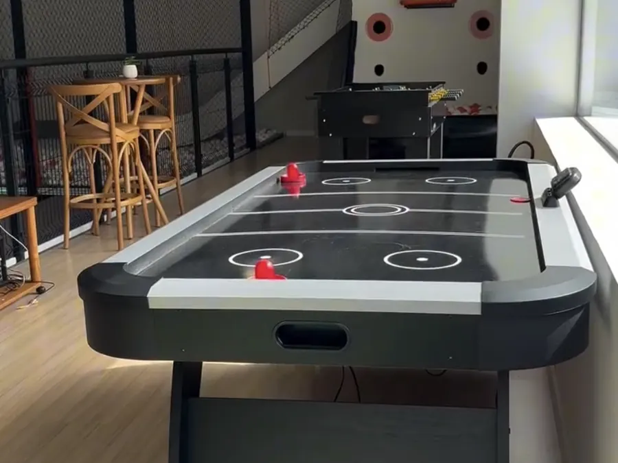 Área de jogos com mesa de air hockey e pebolim no mezanino