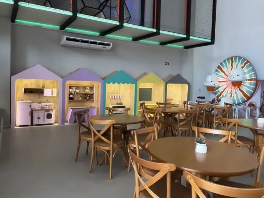 Salão do Espaço Anni Felici com mesas, casinhas de brincar e mini roda-gigante