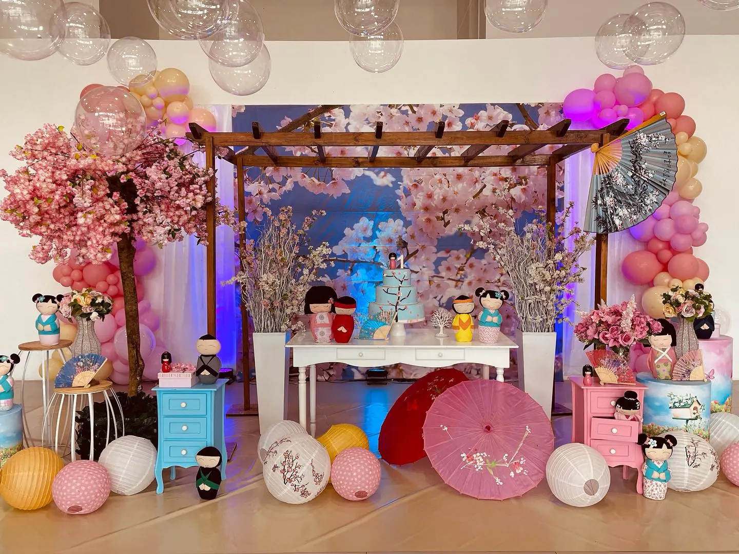 Mesa de festa infantil com decoração temática japonesa, cerejeiras e bonecas kokeshi no Espaço Anni Felici